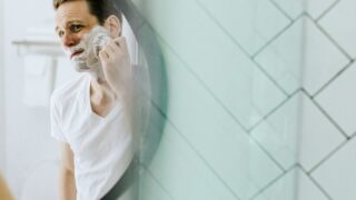 鏡の前でひげを剃る男性
